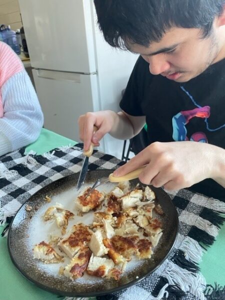 Person eating a pizza with a knife and fork